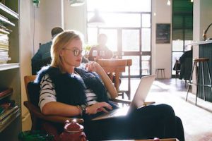 woman sitting in cafe typing on laptop