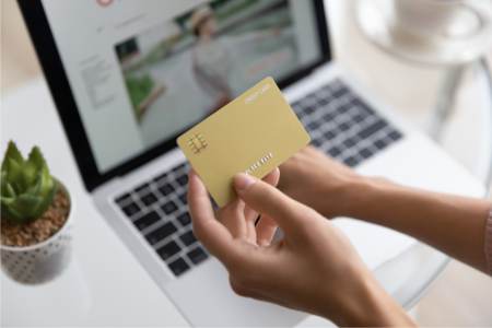 Person holding a credit card and reviewing eCommerce platform pricing