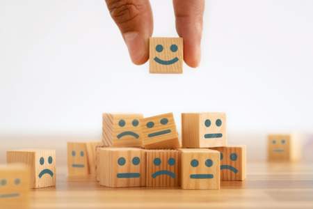 Wooden block with smiley face atop other blocks with neutral or upset faces