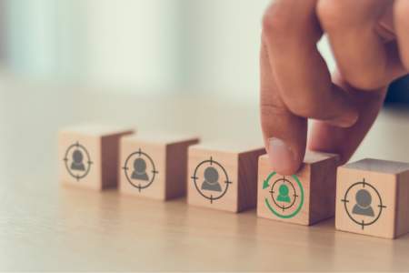 Hand selecting a wooden block with a green target symbol among other blocks