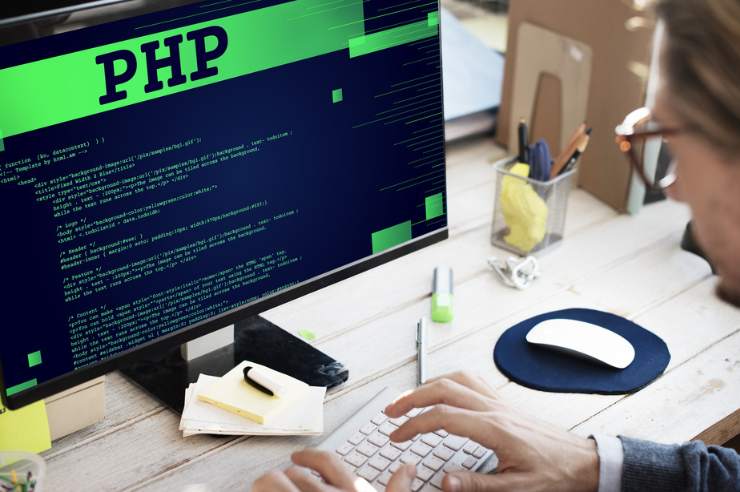 Web developer demonstrating the relevance of PHP by coding on a desktop