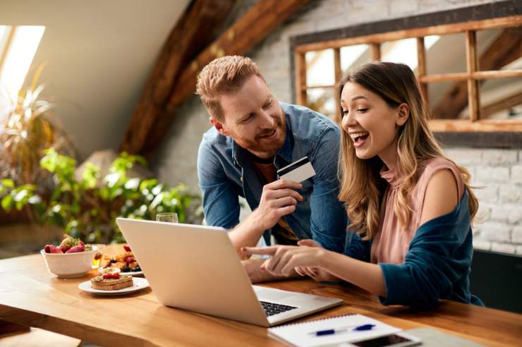 Man with credit card shopping online with woman at desk