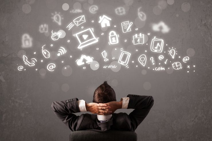 man sitting at a desk with tech symbols over his head