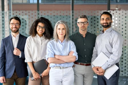 Five employees of a digital marketing agency for law firms standing in a row and smiling at the camera.