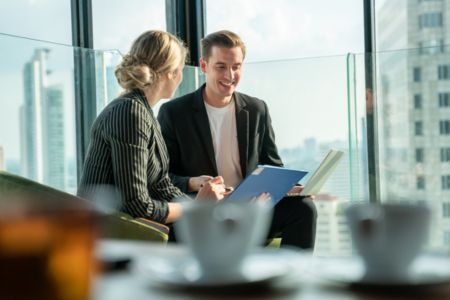 man and woman talking about deals in front of computers.