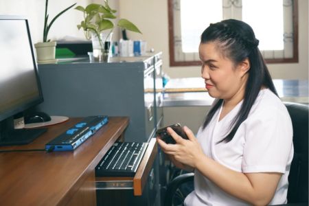 Woman at computer desk using assistive technology to access the internet.