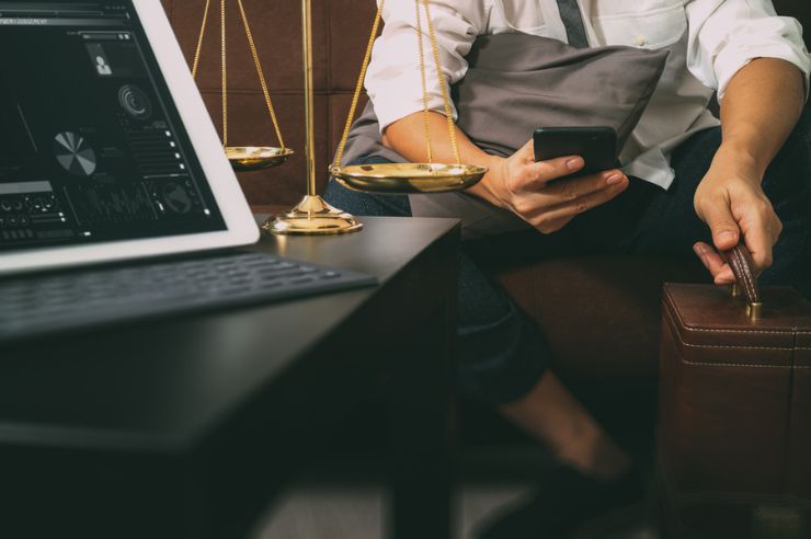 a computer with data statistics and a lawyer checking his phone in the background