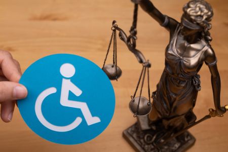 Justice statue with hand holding wheelchair image.