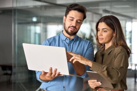 SEO specialist stands with a client looking at a laptop