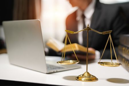 scales of justice on desk lawyer reading in the background