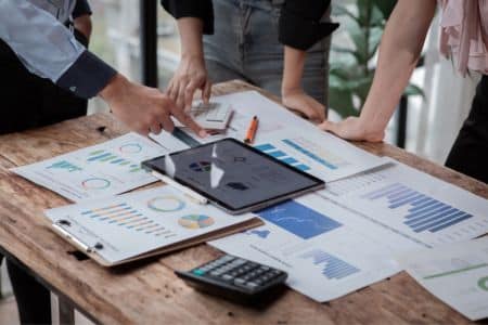 team discussing financial charts and graphs on a table with a digital tablet