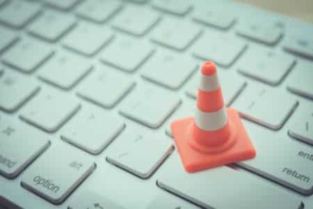 small warning cone placed on a computer keyboard indicating blocked clicks.