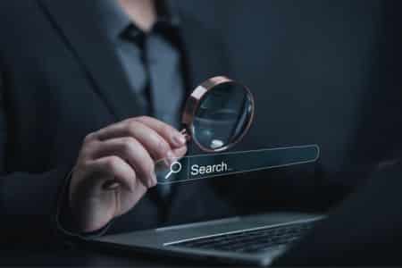 business professional examining online search results with a magnifying glass.