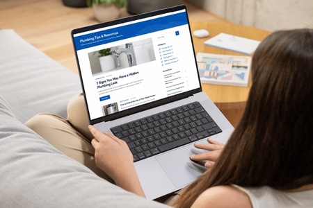 woman on laptop researching plumbing companies on laptop